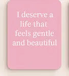 Pink notebook with text 'I deserve a life that feels gentle and beautiful' on a pink background