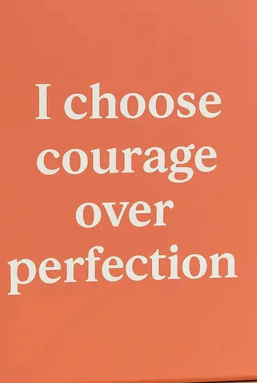Coral-colored box with 'I choose courage over perfection' text on a beige background